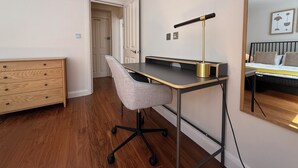 Un dormitorio moderno con cama, mesita de noche y escritorio con silla.