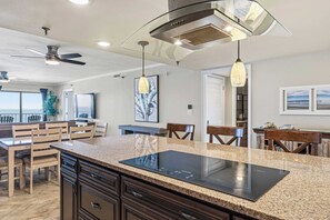 Una cocina moderna con encimera de granito, placa de inducción negra y ventilador de techo.