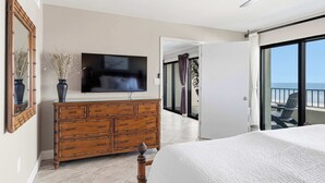 Un dormitorio con cama, cómoda, televisor y balcón con vistas.