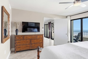 Ein Schlafzimmer mit Bett, Kommode, Fernseher und einem Balkon mit Blick.