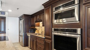 Una cocina moderna con armarios de madera oscura, electrodomésticos de acero inoxidable y encimera de granito.