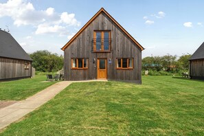 Une maison en bois avec un porche à l’avant, une porte centrale et une petite fenêtre au-dessus de la porte.