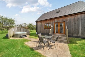 A wooden building with a hot tub, outdoor seating, and a fenced yard. - Lodge 4 - Pavilion (Brigg)