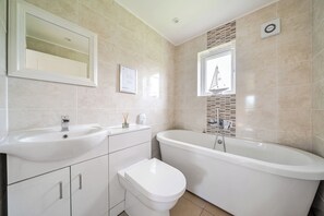 Une salle de bain moderne avec un double vasque, des toilettes et une baignoire sur pieds.
