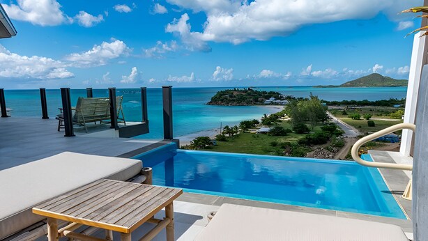 Zona de piscina con vista al océano y una pequeña isla.