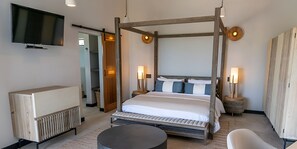 A modern bedroom with a four-poster bed, bedside lamps, a flat-screen TV, and a wooden wardrobe. - Sunset Vista: Luxury 2-Bedroom Ocean-View Suite with Pool & Sauna, Antigua (Urlings)