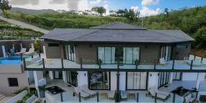 A modern two-story house with a rooftop pool, large windows, and a balcony with outdoor seating. - Sunset Vista: Luxury 2-Bedroom Ocean-View Suite with Pool & Sauna, Antigua (Urlings)