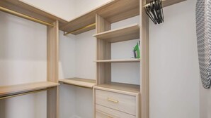 En walk-in garderobe med åbne hylder, en bøjlestang og en skuffeeenhed.