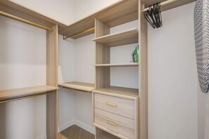 Ein begehbarer Kleiderschrank mit offenen Regalen, einer Kleiderstange und einer Schubladenkommode.