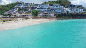 Une station balnéaire dotée de plusieurs bâtiments, d’une plage de sable et d’une mer turquoise aux eaux limpides.