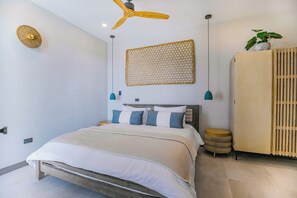 A modern bedroom with a bed, a ceiling fan, a wall-mounted woven panel, and a wardrobe. - Seastar: Luxury 2-Bedroom Ocean-View Suite with Private Pool, Antigua (Urlings)