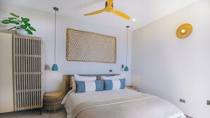 Une chambre à coucher comprenant un lit, un ventilateur de plafond, un luminaire fixé au mur et un panneau décoratif mural.