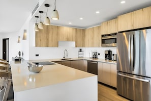 Una cocina moderna con una isla grande, electrodomésticos de acero inoxidable y armarios de madera.