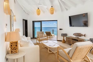 A modern living room with a large TV, comfortable seating, and a view of the ocean. - Ocean 19: Luxury 3-Bedroom Oceanfront Suite, Ffryes Beach, Antigua (Urlings)