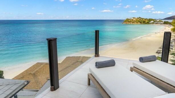 Una habitación junto a la playa con vista al océano y a la arena.