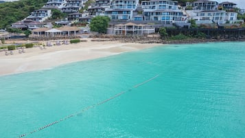 A coastal resort with multiple buildings, a sandy beach, and a clear turquoise sea.