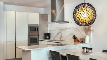 A modern kitchen with a central island, stainless steel appliances, and a unique pendant light.