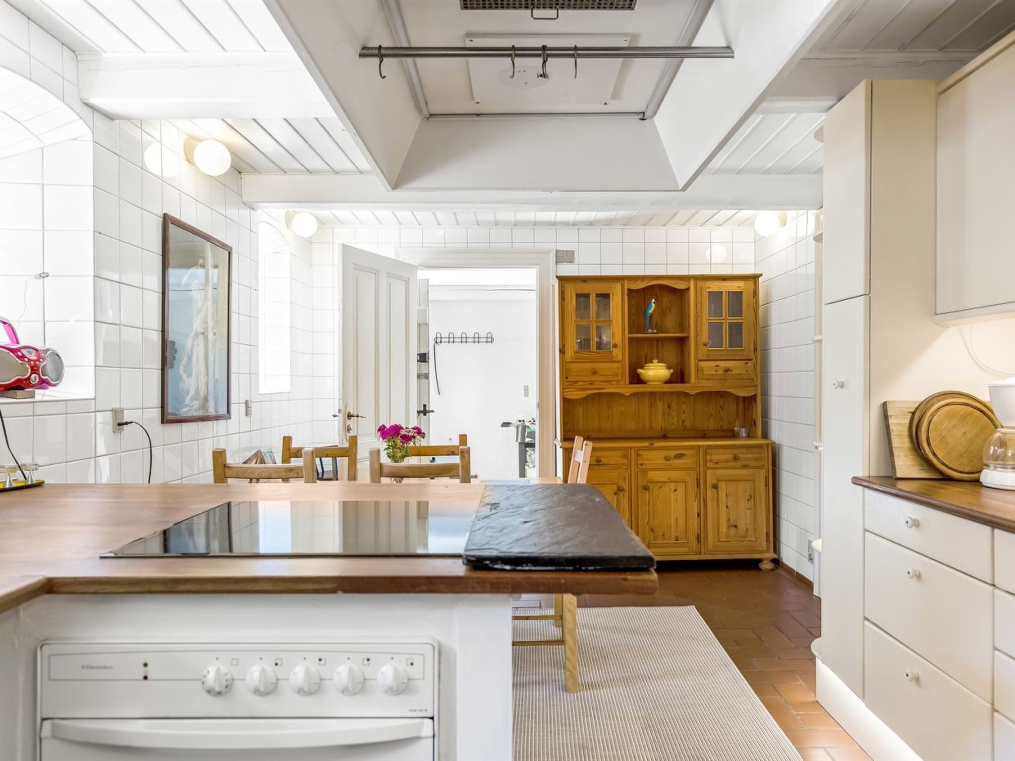 A modern kitchen with white cabinetry, a central island with a stove, and wooden accents.