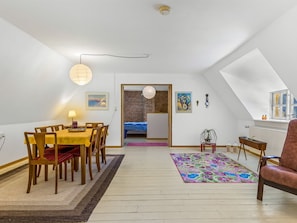 Ein Zimmer mit Esstisch, Stühlen, einem Bett, einem farbenfrohen Teppich und einem Fenster mit Aussicht.