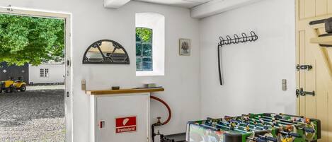 Una habitación con mesa de fútbolín, extintor Brandmayer, una ventana y una puerta.