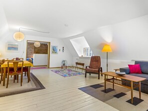 Un amplio loft con comedor, sala de estar con sofá y sillón, y tragaluz.