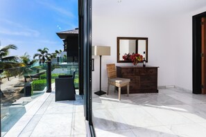 Ein modernes Zimmer mit Glastür zum Balkon, ein Korbstuhl, eine Holzkommode und ein Spiegel.