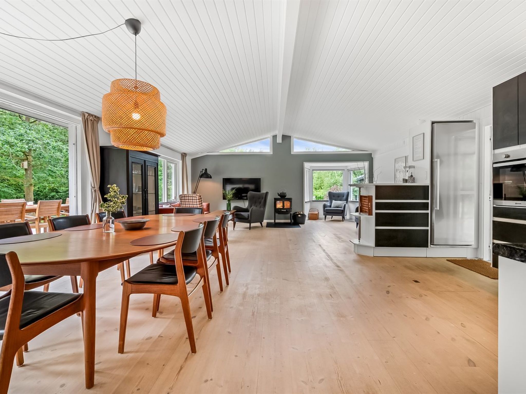 A spacious kitchen with a dining area, wooden flooring, and a large window providing natural light.