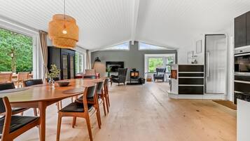 A spacious kitchen with a dining area, wooden flooring, and a large window providing natural light.