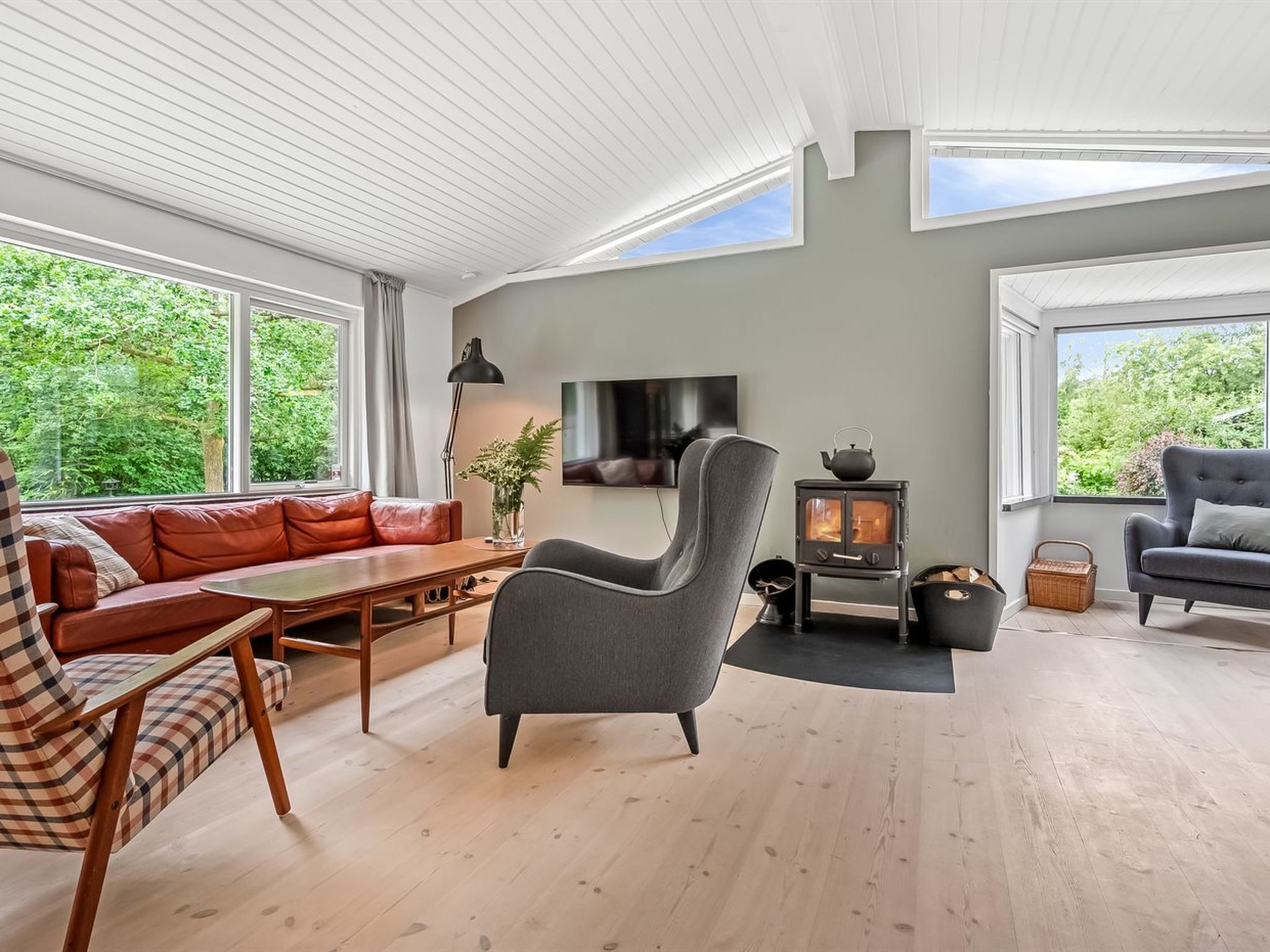 Un salon moderne avec un canapé, un fauteuil et un téléviseur.