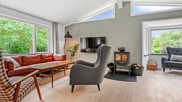 Un salon moderne avec un canapé, un fauteuil et un téléviseur.