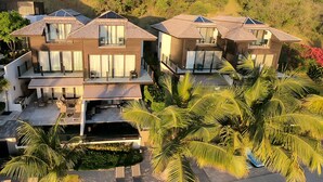 A modern multi-story residential building with a flat roof, large windows, and a balcony. - Beach House 5: Luxury 3-Bedroom Beach House with Private Pool, Antigua (Urlings)