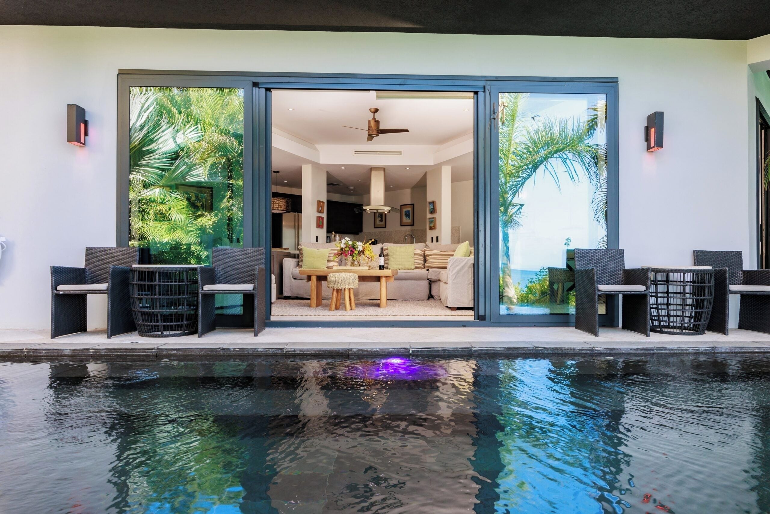 A modern poolside area with a dining setup and a view of the interior.