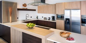 A modern kitchen with a central island, stainless steel appliances, and wooden cabinetry. - Oceanview 2BR Villa with Private Pool & Panoramic Balconies (Urlings)