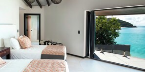Une chambre moderne avec un grand lit, un lit plus petit et une vue sur la mer.