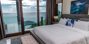 Un dormitorio con una cama grande, vista al océano y un cuadro en la pared.