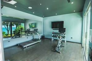 Een moderne sportschool met fitnessapparatuur, een loopband en een rek voor gewichten.