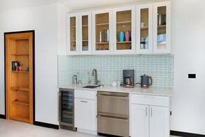 A modern kitchen with white cabinetry, a built-in dishwasher, and a coffee maker on the countertop. - Blue Heaven Rendezvous: Resort's Largest Entertaining Villa, Antigua (Urlings)