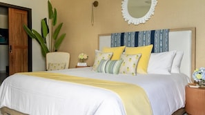 A bedroom with a bed, a nightstand, a mirror, and a potted plant.