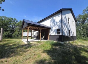 Una casa moderna de dos pisos con un porche cubierto y una pequeña terraza.