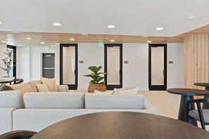 A modern waiting area with a sectional sofa, a round table, and a potted plant. - Top Floor! Pool | Spa| Bowling| Parking| King Bed! (Salt Lake City)