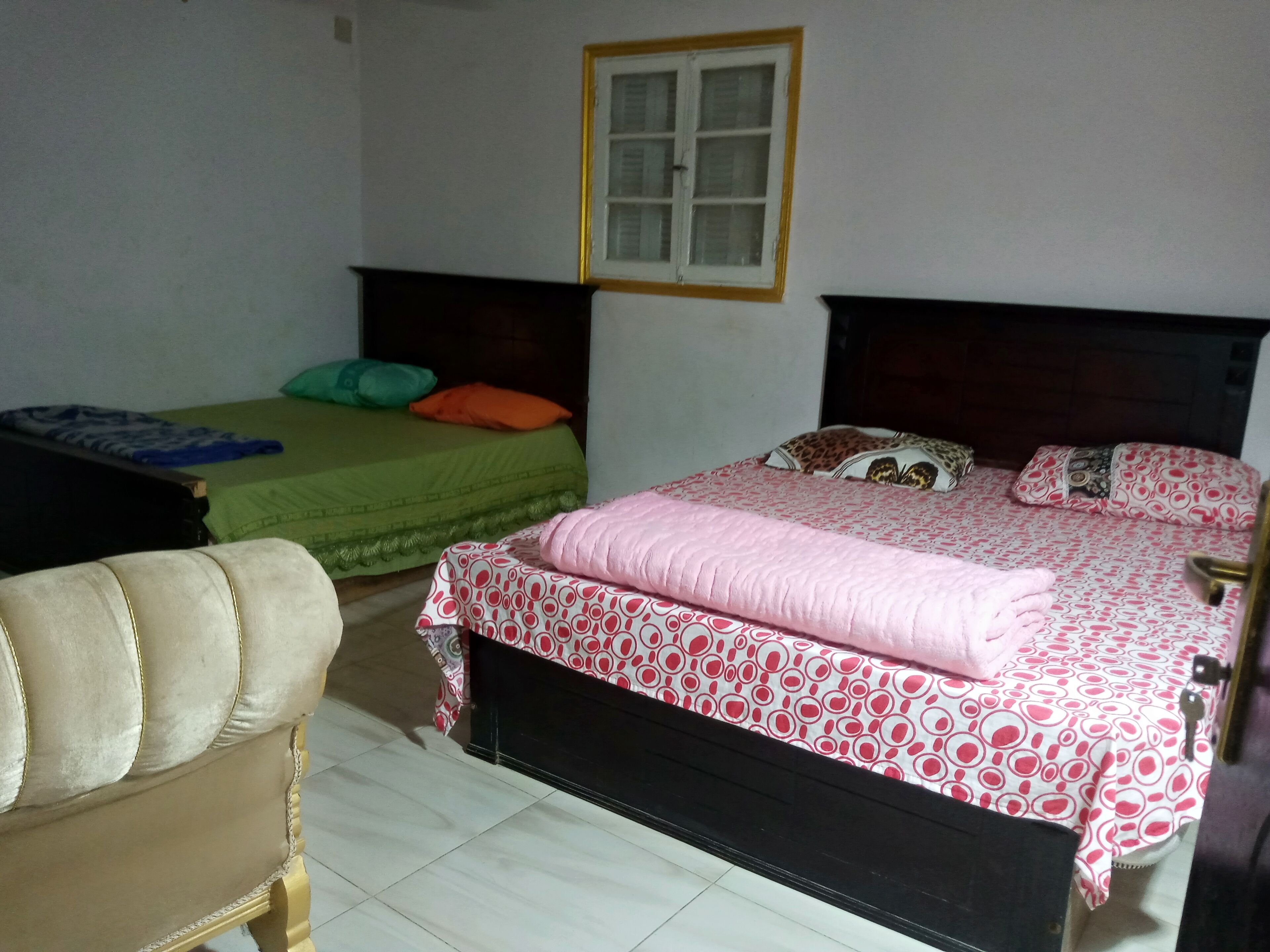 Un dormitorio con dos camas individuales, un sofá y una ventana.