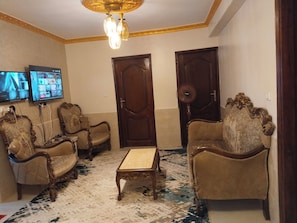 A room with two sofas, a coffee table, and a TV mounted on the wall. - Mony Pyramids  (Cairo)
