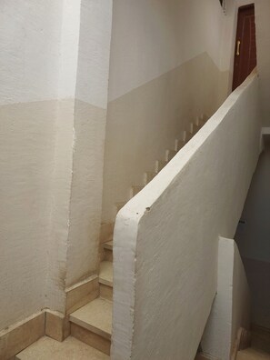 Una escalera con paredes blancas y una puerta marrón en la parte superior.