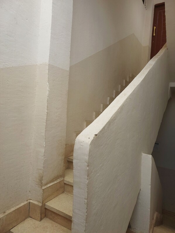 A staircase with white walls and a brown door at the top. - Mony Pyramids (Giza)