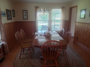 Uma sala de jantar com uma mesa de madeira, seis cadeiras e um candelabro.