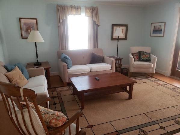 Una sala de estar con sofá, sillón, mesa de centro y alfombra.