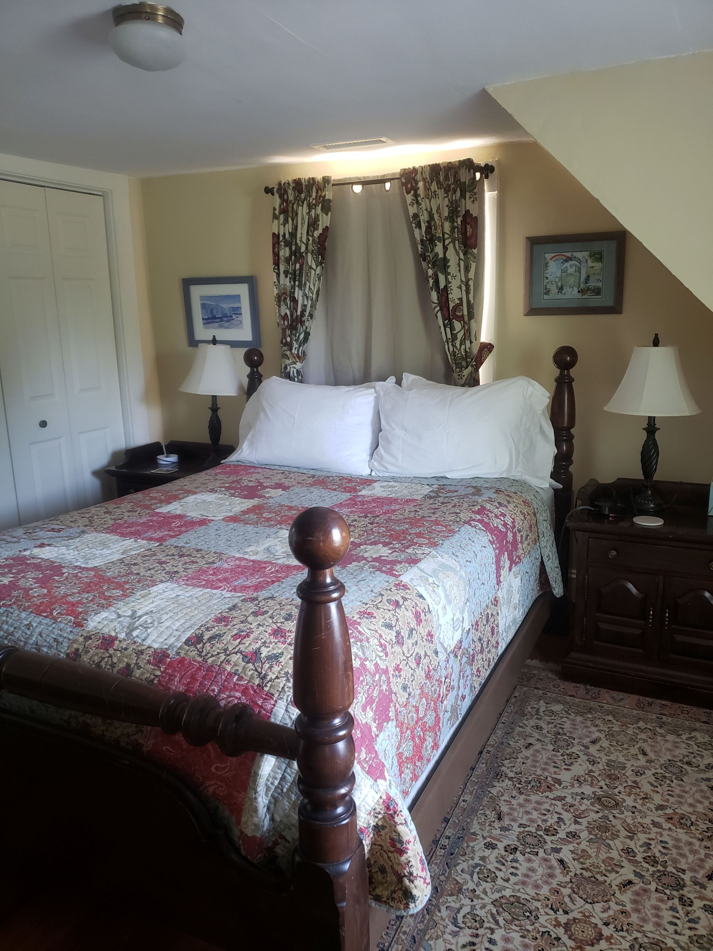 Une chambre à coucher avec un lit, deux tables de chevet avec des lampes, une porte et un tableau encadré au mur.
