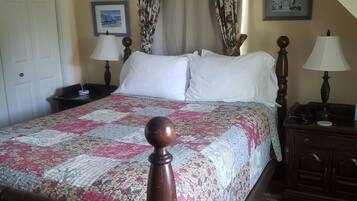 Une chambre à coucher avec un lit, deux tables de chevet avec des lampes, une porte et un tableau encadré au mur.