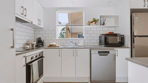Eine moderne Küche mit weißen Schränken, einem Edelstahl-Kühlschrank, einer Mikrowelle und einem Geschirrspüler.