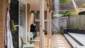 Ein Patio mit Tisch und Stühlen, einer hängenden Tasche und einem Wasserspiel.